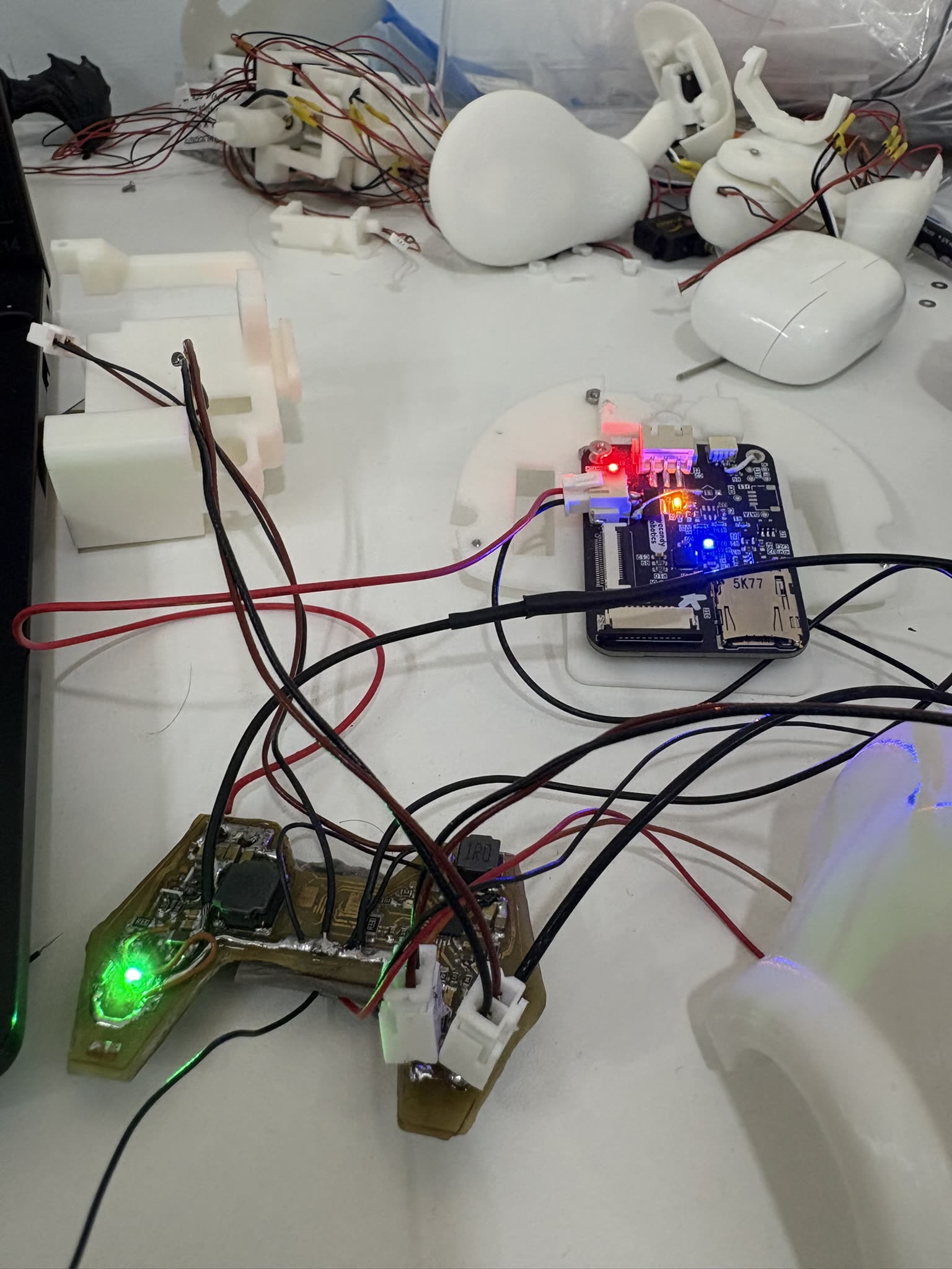Bench covered in printed parts, a compute module and two boards with LEDs lit